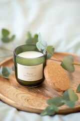 Fototapeta na wymiar Green scented candle and a branch of eucalyptus on a wooden tray.