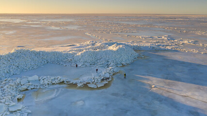 Aerial view to the group of unidentified people exploring the high mounds of cracked ice sheets, piled up by last storm 