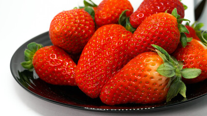 Fresas en fondo blanco sobre un plato negro