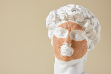copy of the head of an antique statue of David with a face mask made of cosmetic clay