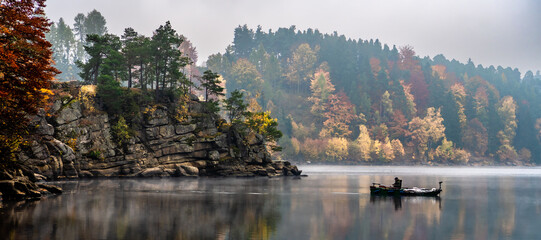 Foggy Landscape With Fishermans Boat On Calm Lake And Autumnal Forest At Lake Ottenstein In Austria