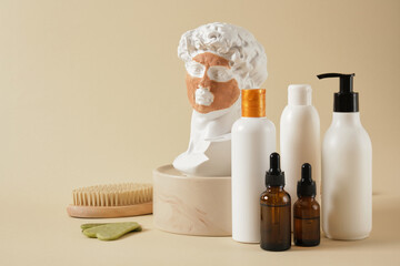 a copy of the antique sculpture of David with a mask of cosmetic clay on his face, massage brushes and cosmetic bottles