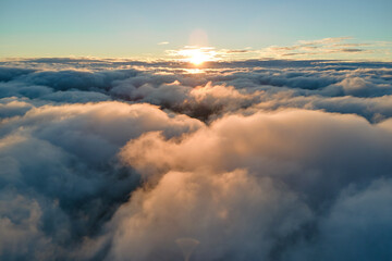Aerial view from airplane window at high altitude of dense puffy cumulus clouds flying in evening