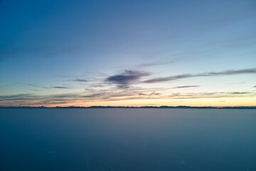 Fototapeta na wymiar Aerial view of colorful sunset over white dense foggy clouds cover with distant dark silhouettes of mountain hills on horizon