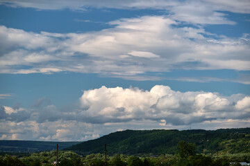 Bright landscape of white puffy cumulus clouds on blue clear sky over rural area