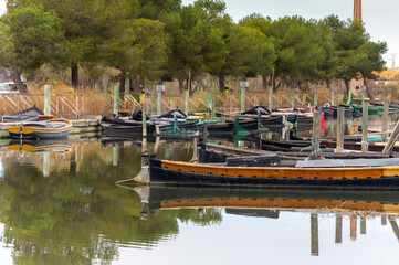 barcos de madera amarrados a los muelles y pasarelas de madera, en el puerto de Catarroja ,en la albufera de valencia ,con un cielo nublado .