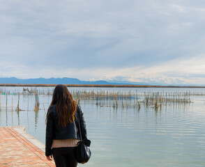 mujer paseando por el muelle del embarcadero de puchol ,con las redes típicas de pesca de la zona llamadas , mornell , con un bonito cielo nublado .