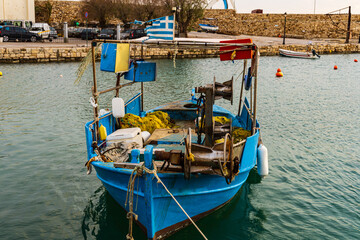 Fototapeta premium Scenic shot of a calm fisher boat with a scenic sunrise at the greek harbor of Rethymno old town in Crete, Greece