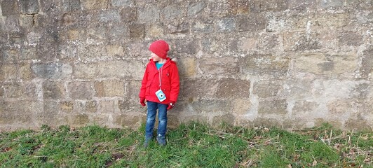 a 4-year boy dressed in a red jacket and hat and jeans. 