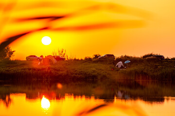 Sunrise over the river , golden sun in river , cars on the beach , reflections on water 