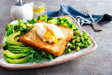 Whole wheat toasted bread with avocado, poached egg, pea on plate. Top view. Healthy diet breakfast