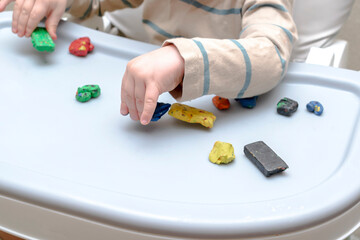 Cute little childrens hands playing at home, molding multi-colored plasticine, sculpts with colored clay stucco. Playdough, clay modeling.art creativity, craft at daycare, kindergarten