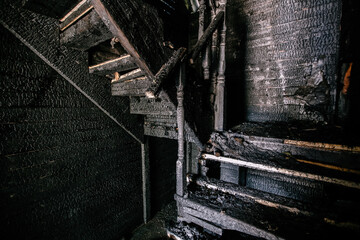 Burnt wooden house interior. Charred stairs and walls. Consequences of fire