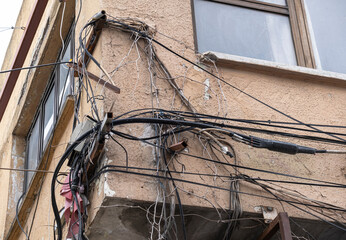 tangled messy cables on old building wall.