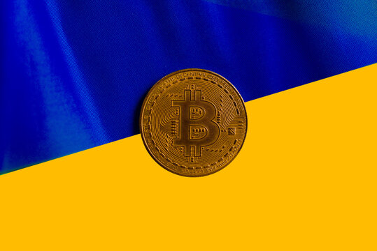 Bitcoin on the background of the Ukrainian flag. The concept of the cryptocurrency market against the backdrop of the war in Ukraine