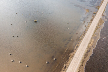 Flood in spring day. Gravel road. Hay rolls are located in flooded meadow water in spring. Aerial view.
