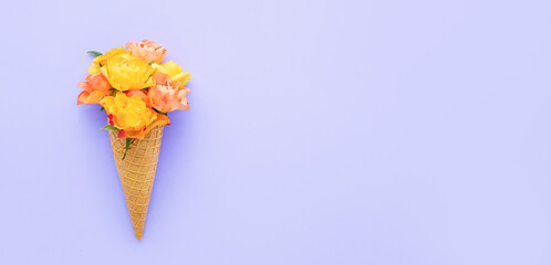 Yellow roses in a waffle ice cream cone on a lilac background. Summer concept, banner