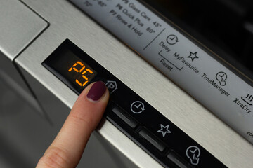 A person is selecting a program on a dishwasher. 