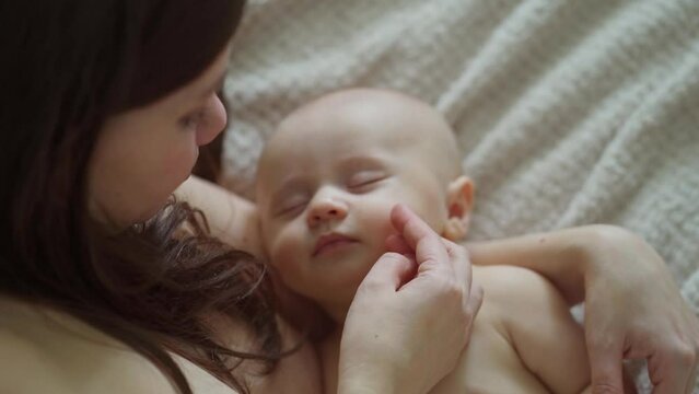 a beautiful naked baby sleeps in his mother's arms. the happiness of motherhood.