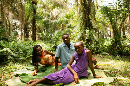 portrait shot of a black african family of farmers sitting in the rainforest 