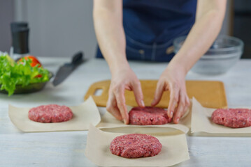 Woman's hand forming a beef meat for a hamburger party. Portioning ground meat. Homemade burgers. Making food at home. close up