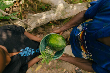 Black hands holding a basket of fresh fruit harvest in a rainforest 