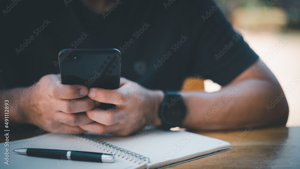 Poster close up on casual man using smart phone, using mobile smart phone and online working on laptop comp