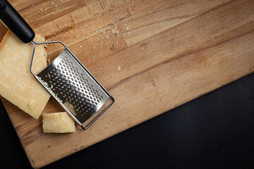 Parmesan cheese grated with a grater on a cutting board placed in an angle of the frame