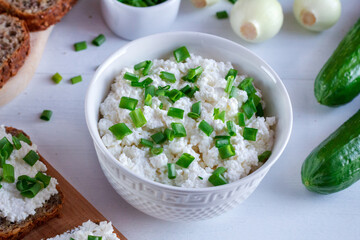 Zdrowe wiosenne śniadanie złożone z twarogu ze szczypiorkiem, razowego chleba i świeżego ogórka