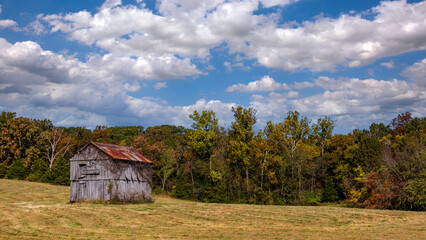 Old weatherworn barn in a rural countryside field under a cloudy sky in Missouri