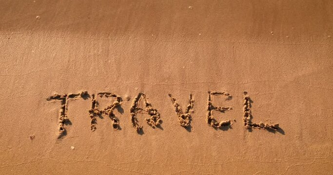 Travel word on the sand. The written word travel on the sea shore. A concept of attractive summer vacation and tourism in summer.