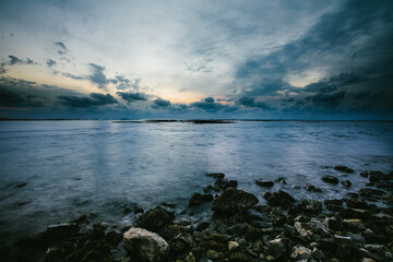 Fototapeta na wymiar Ocean waves over the rocky beach with a blue sky and clouds