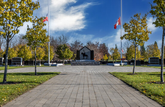 The Royal Canadian Mounted Police memorial to fallen officers, flags at half mast, paving stone walkway in foreground, daytime sunny, nobody