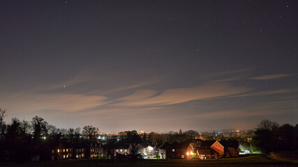 starry night with clouds over suburban homes