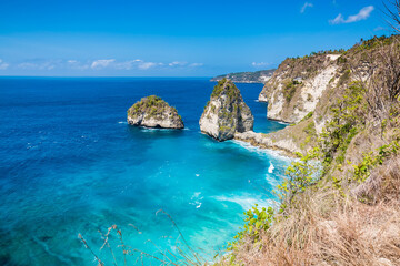 Fototapeta na wymiar Amazing tropical view of a secret beach with cliffs and blue ocean in Nusa Penida, Indonesia.