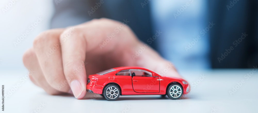 Wall mural businessman hand holding red car toy. Car insurance, warranty, rental, Financial, new and repair concept