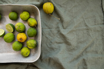 Garden picked limes in a rustic tray on a green linen towel 