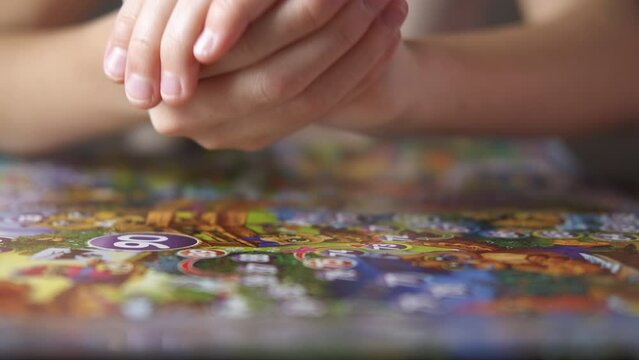 Board game in room. A child hands throw a dice on the table with board game.