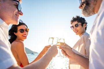 Group of man and woman friends enjoy party drinking champagne with talking together while catamaran...