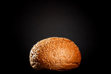 burger bun with sesame seeds on black background..
