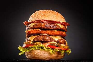 Double burger with bacon grilled yellow cheese onions tomatoes cucumber and lettuce. Isolated on...