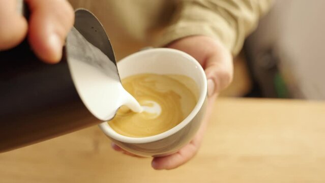 milk is poured on coffee to make latte art heart