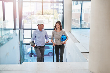 Here come the sight surveyors. High angle shot of two businesspeople walking into the lobby of...