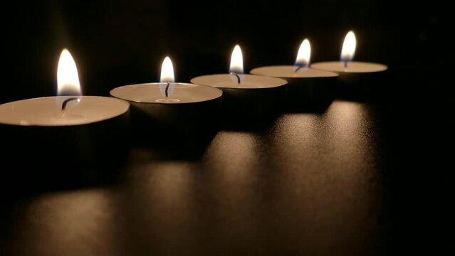 Footage of several candles lined up in a row and burning