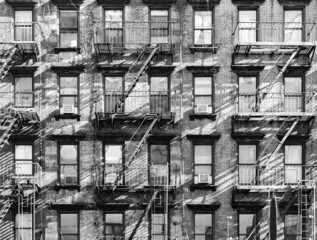 Exterior view of old apartment buildings with windows and fire escapes in New York City in black...