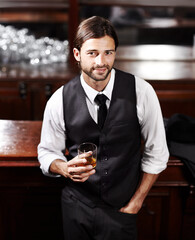 Just taking it easy. Portrait of a well-dressed young man sitting at a bar with a drink.