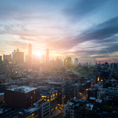 New York City skyline at dusk with sunlight shining behind the buildings of Lower Manhattan - obrazy, fototapety, plakaty