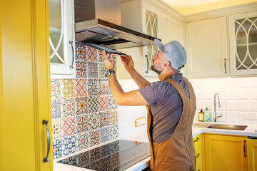 electrician repairs the hood in the kitchen - 491123871