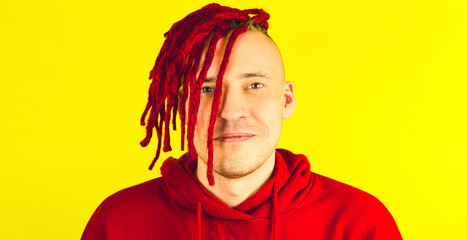 Young man with red dreadlocks looking at camera. Smiling male expressing positive emotions.