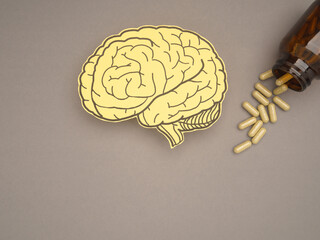 Brain shape made from paper and pills capsules with a bottle on a gray background